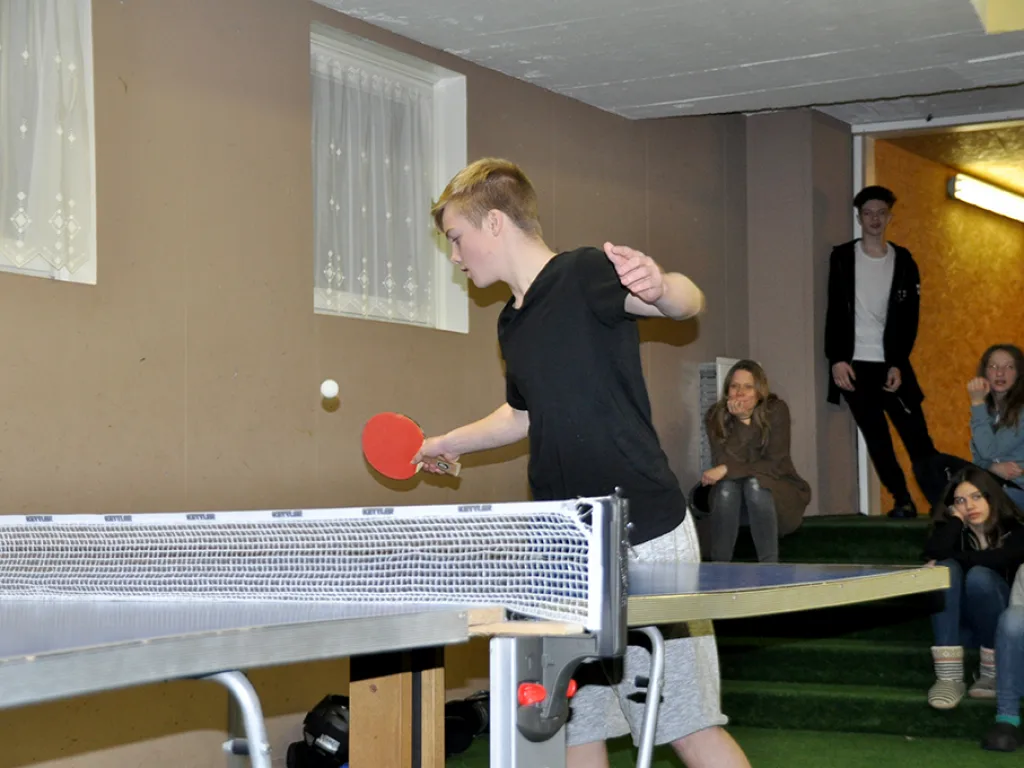 Jugendlicher spielt Tischtennis im Aufenthaltsraum.